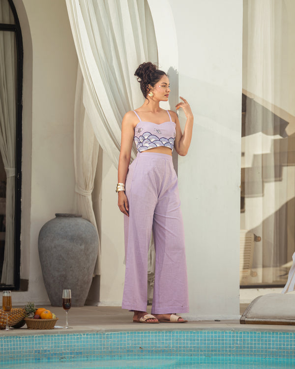 woman wearing lavender cotton slub embroidered co-ord set with sleeveless crop top and relaxed pants in a summer resort setting