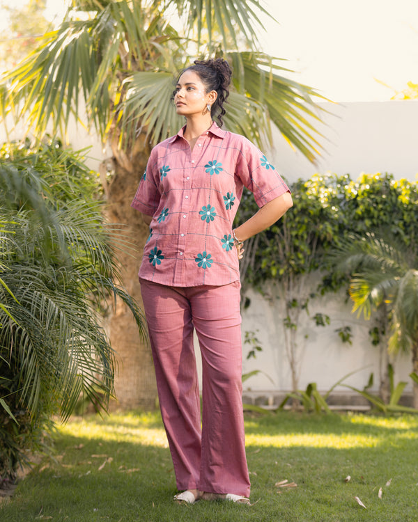 Woman wearing a pink outfit with floral patterns in an outdoor setting