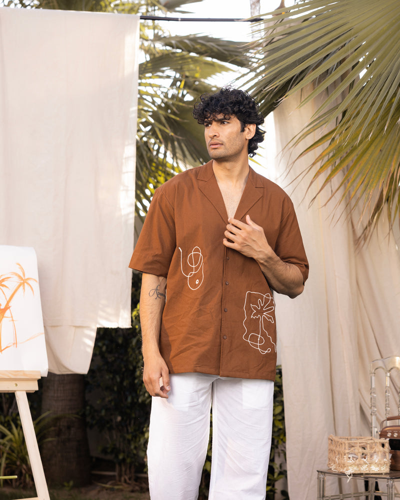 Man wearing a brown shirt with white patterns outdoors