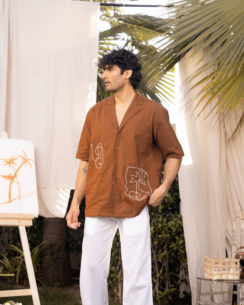 Man wearing a brown shirt with white patterns in an outdoor setting