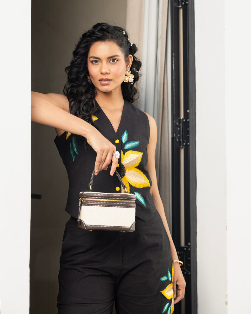 Women’s black embroidered outfit detail with floral motif on pants and waistcoat top