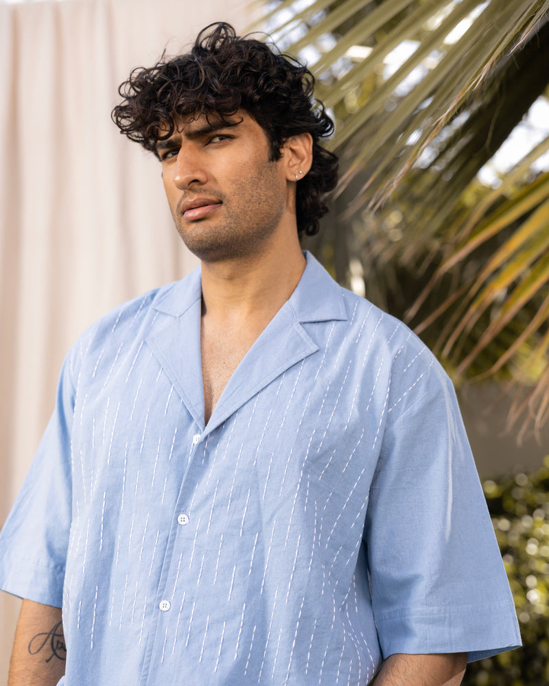 Man wearing a light blue shirt with a blurred natural background