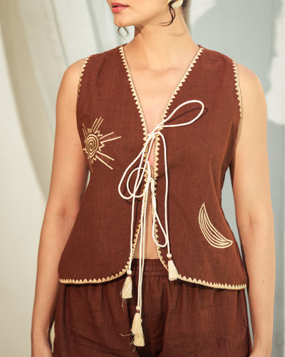Brown embroidered vest with white accents on a neutral background
