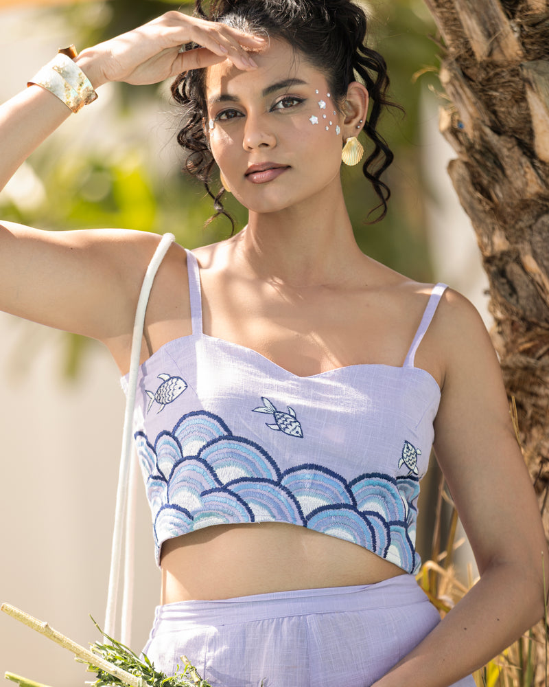 Woman wearing a light purple top with fish designs outdoors
