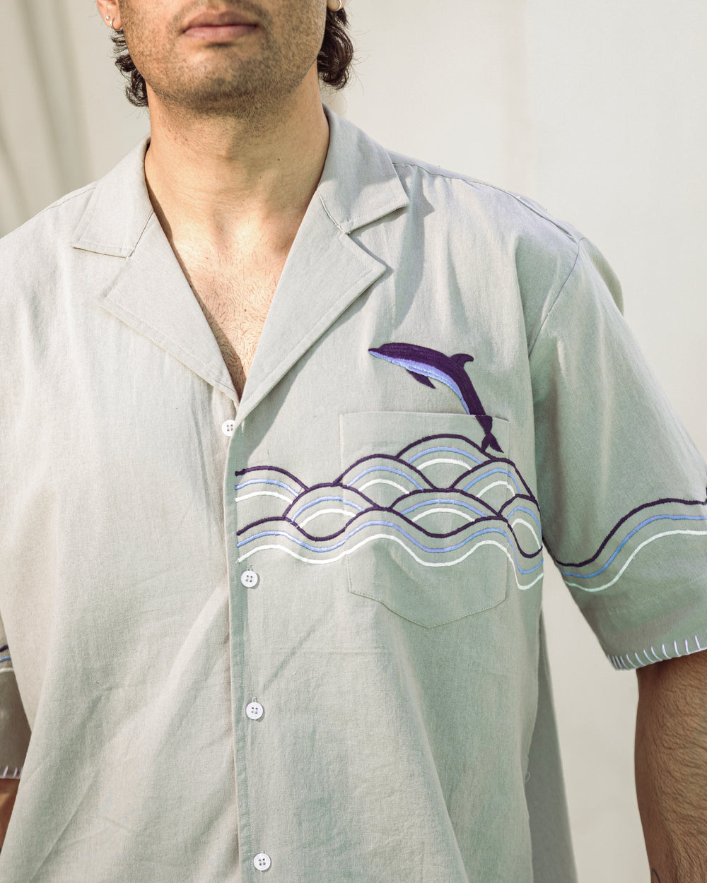 Light gray shirt with dolphin and wave design worn by a person