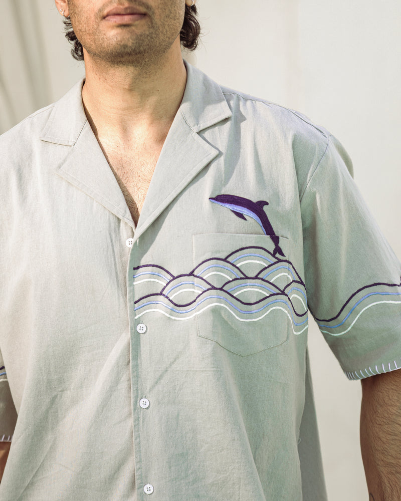 Light gray shirt with dolphin and wave design worn by a person
