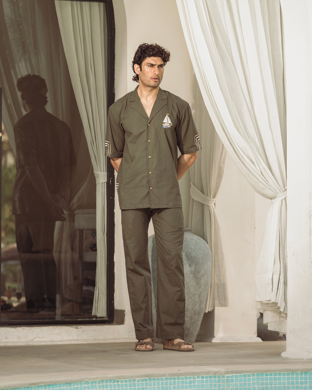 Man standing by a poolside with curtains in the background