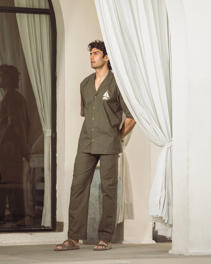 Man in a green outfit standing in front of white curtains