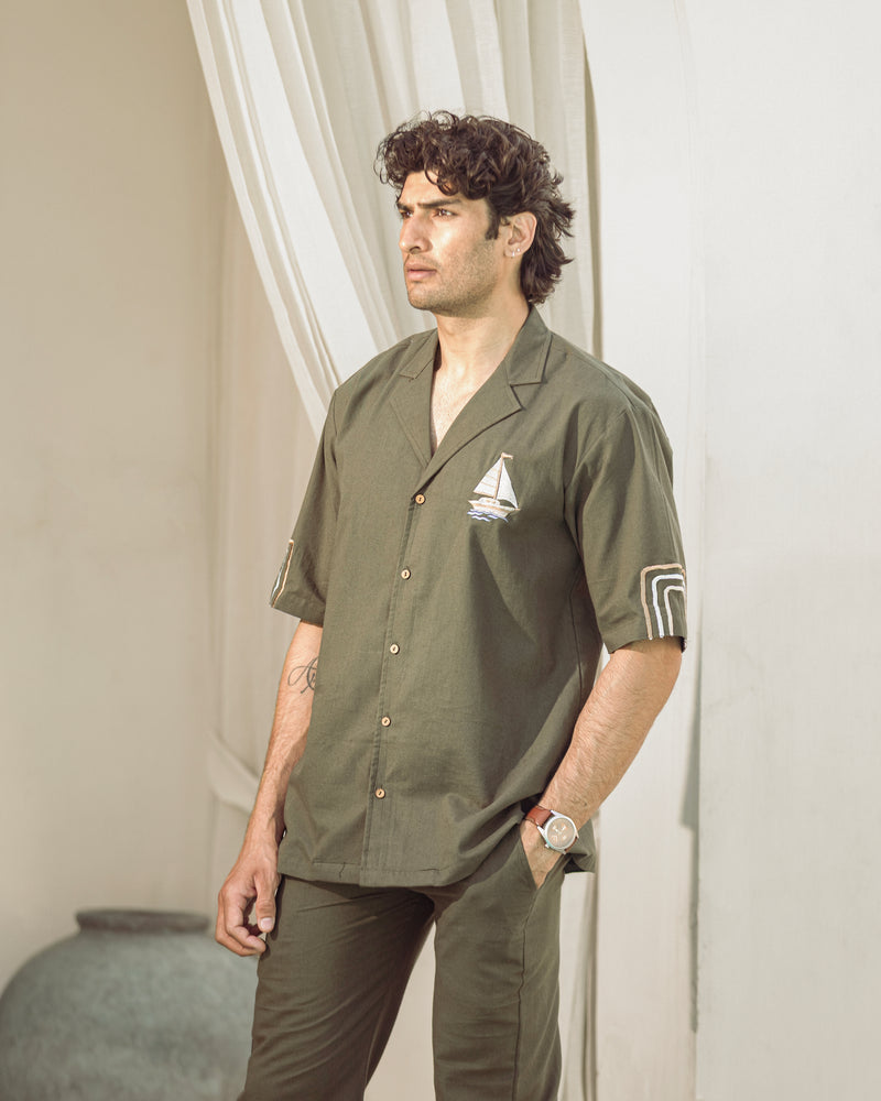 Man wearing a green shirt with a logo, standing against a neutral background