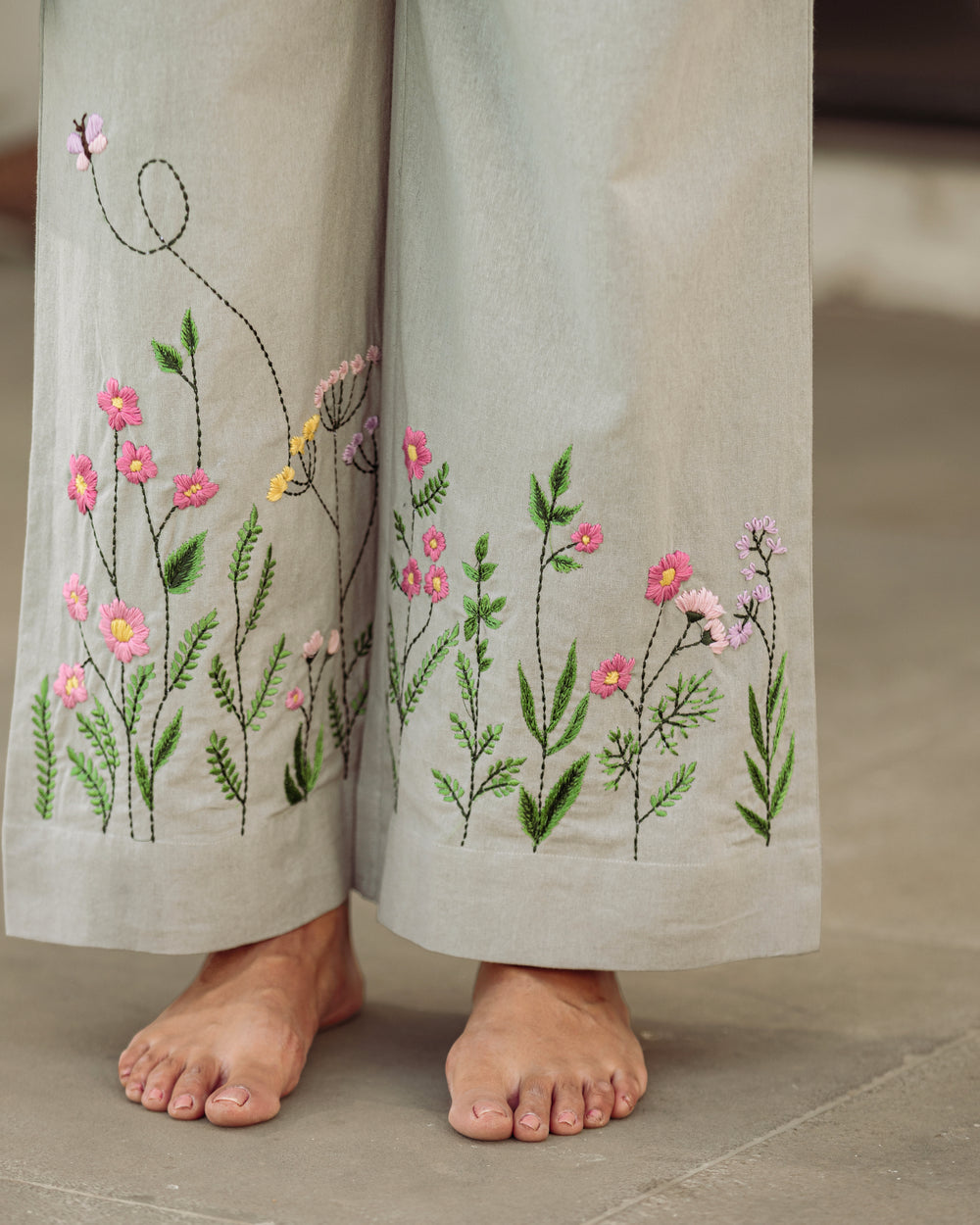 Embroidered pants with floral designs on a neutral background