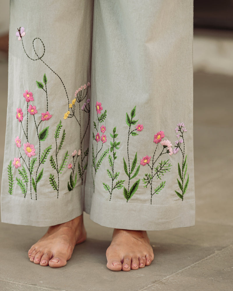 Embroidered pants with floral designs on a neutral background
