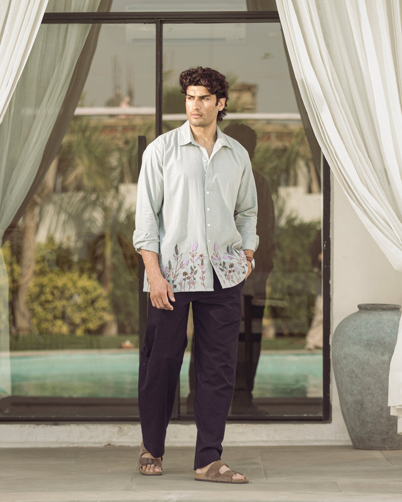 Man standing in a modern indoor setting with large windows and decorative elements.

