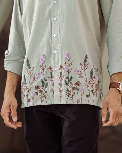 Light gray shirt with floral embroidery on a neutral background


