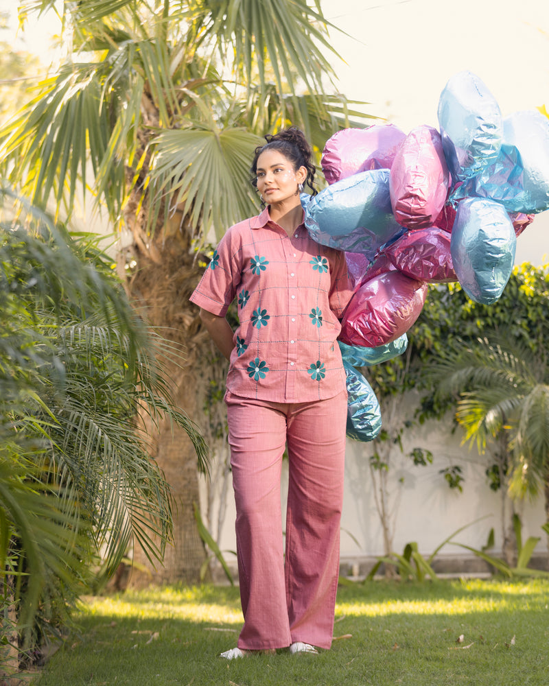 Woman in pink floral outfit holding colorful balloons outdoors