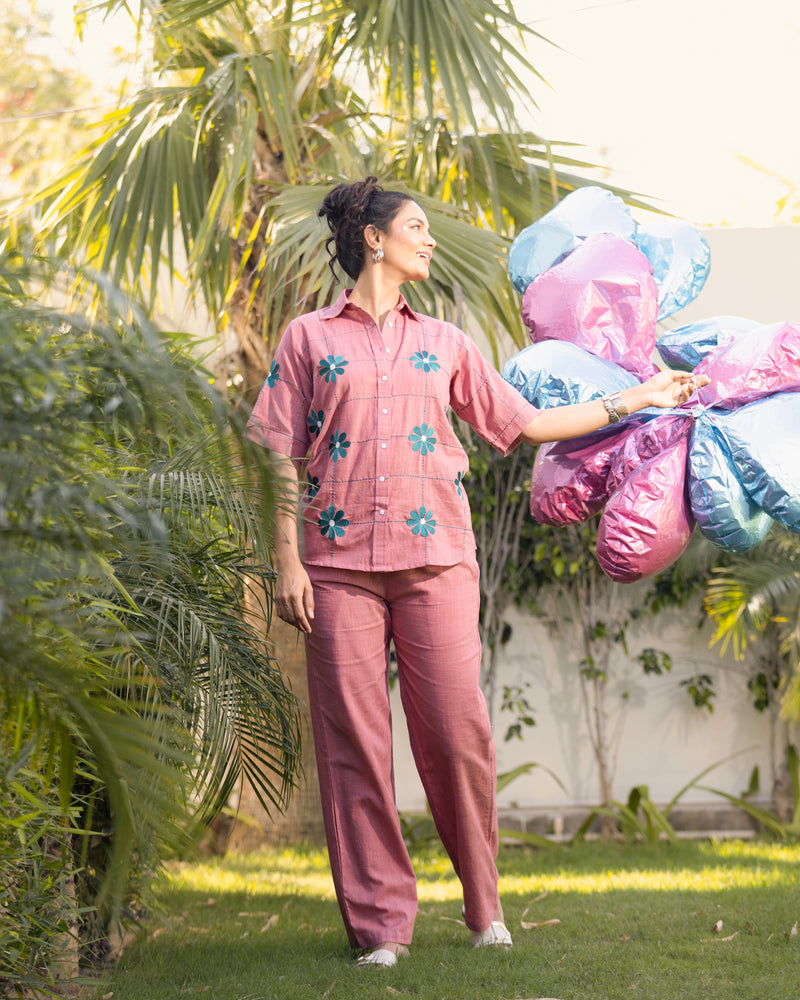 Woman in pink floral outfit holding colorful balloons outdoors