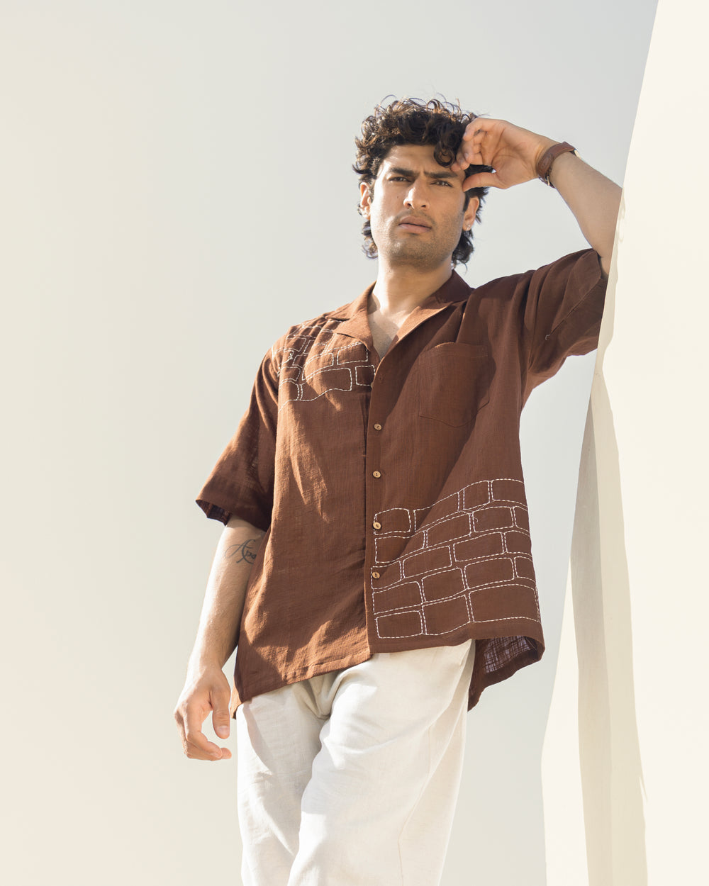 Man wearing a brown shirt with geometric patterns against a light background