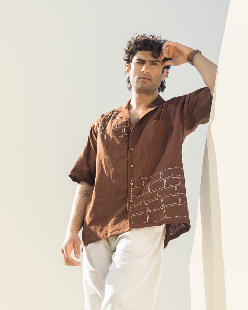 Man wearing a brown shirt with geometric patterns against a light background