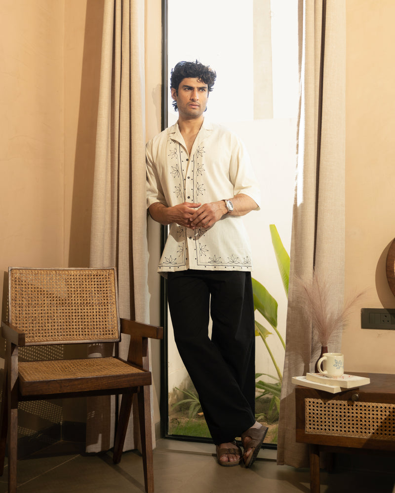 Man standing in a room with a curtain and a chair.

