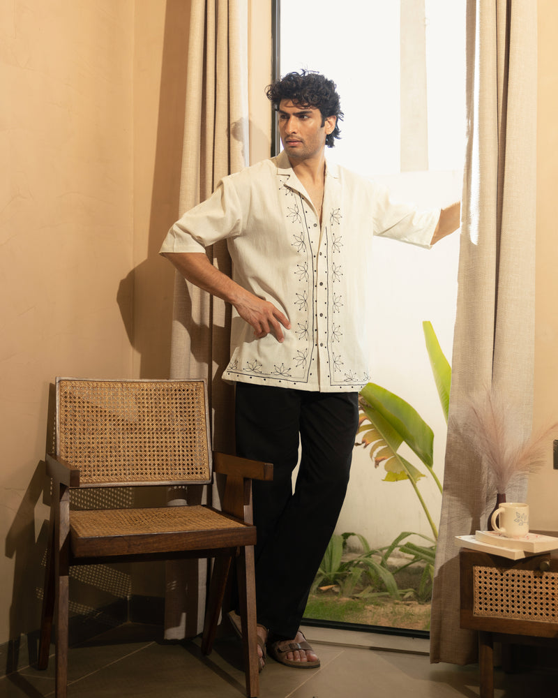 Man standing in a room with a chair and a window in the background

