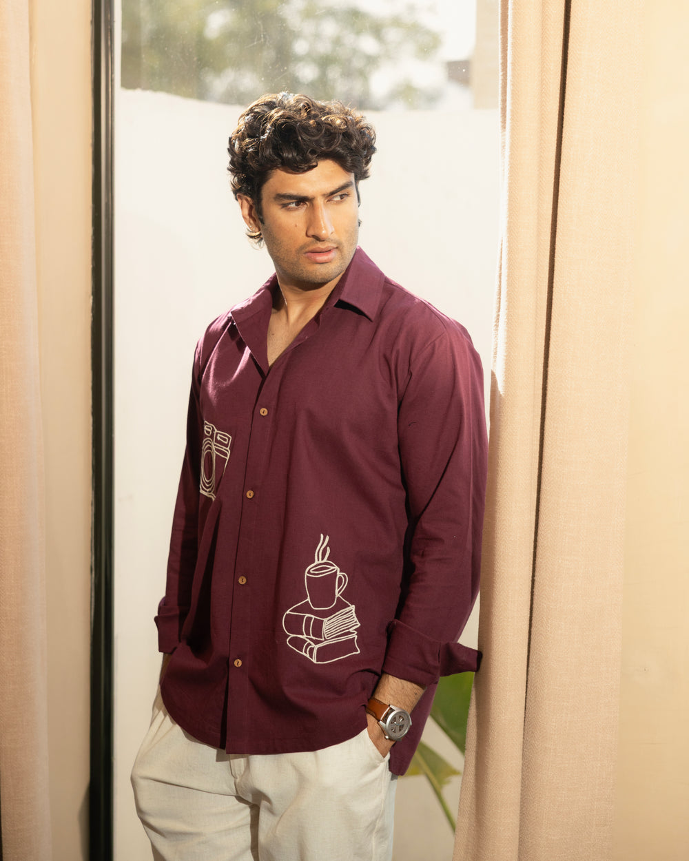 Man wearing a maroon shirt with a design, standing indoors.

