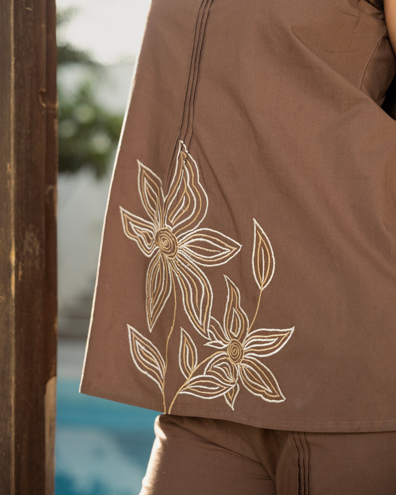 Brown garment with floral embroidery in the background
