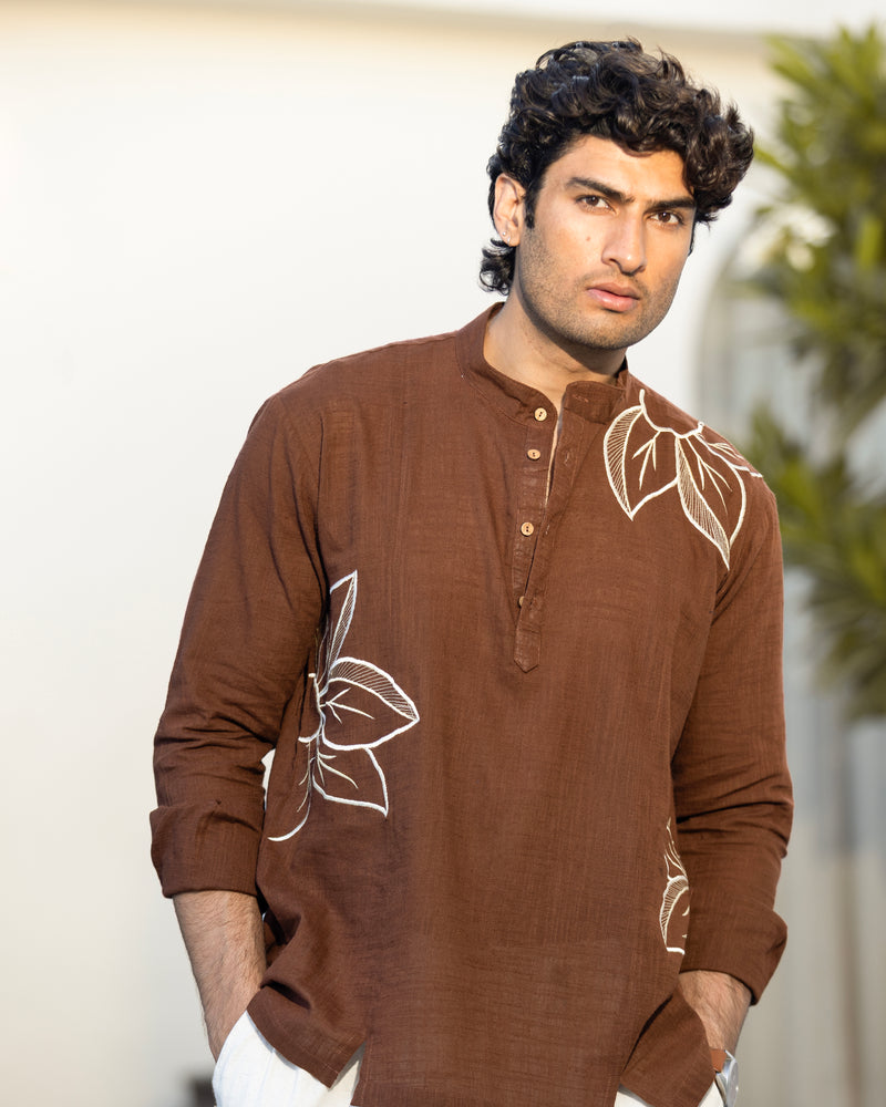 Man wearing a brown kurta with white floral patterns against a neutral background