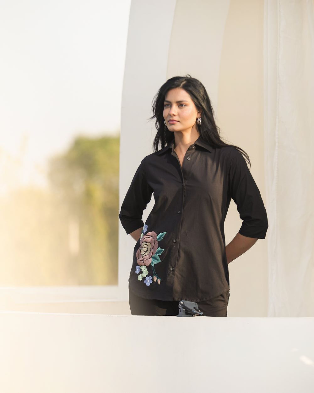 Woman wearing a black shirt with floral embroidery in an outdoor setting